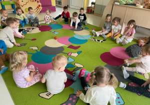 Dzieci podczas zabawy z włóczką na dywanie.