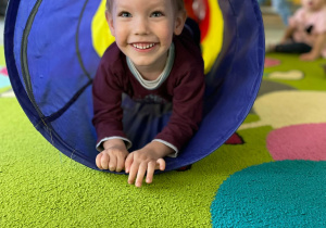 Uśmiechniety chłopiec podczas zabawy w tunelu.