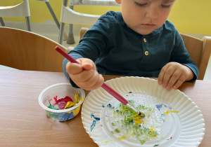 Chłopiec maluje za pomocą farb folię bąbelkową.