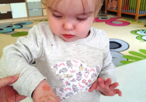 Dziewczynka przygląda się swojemu stempelkowi na dłoni.