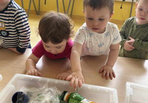 Zdjęcie Mai i Mikołaja przy pojemniku z rekwizytami wykonanymi z plastiku.