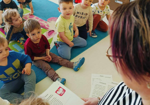 Zdjęcie dzieci słuchających opiekunki, czytającej wiersze o Polsce.