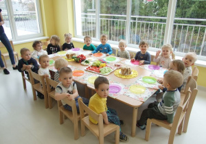 Dzieci siedzą przy stole pełnym warzyw.