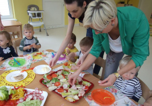 Opiekunki pomagają dekorować kanapki na poczęstunek innych grup.