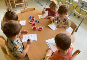 Dzieci z grupy Żabki podczas wykonywania pracy plastycznej.