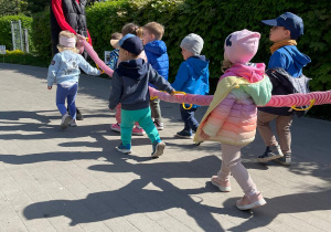 Zdjęcie dzieci trzymających materiałowego węża podczas przechadzki.