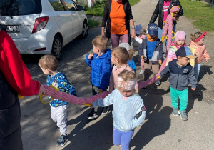 Dzieci wędrujące po okolicy z wężem spacerowym.