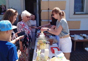 Zdjęcie opiekunek obsługujących gości przy stanowisku z lemoniadą.