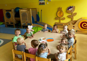 Zdjęcie dzieci siedzących przy stoliczkach, przygotowujących się do zajęć plastycznych z okazji Dnia Dziecka.