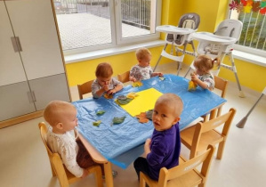Dzieci z grupy Biedroneczki siedzące przy stoliku podczas jesiennej pracy plastycznej.