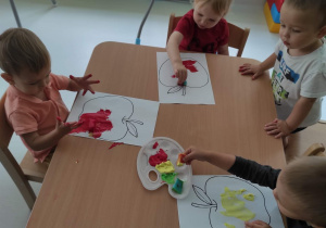 Dzieci z grupy Pszczółki malują farbami za pomocą malutkich gąbeczek jabłuszka.