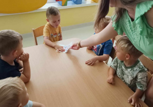Opiekunka daje Leonowi kartkę w formacie A5 z szablonem parasolki do wyklejenia.