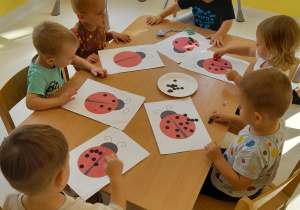 Dzieci z grupy Biedroneczki przy stole podczas zajęć manualnych.