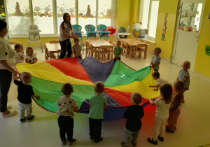 Maluchy wraz z ciociami podczas zabawy chustą animacyjną.