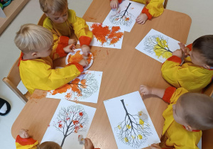 Zdjęcie dzieci siedzących przy stoliczku podczas pracy plastycznej.