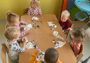 Dzieci z grupy Żabki siedzące przy stoliku podczas pracy plastyczej.