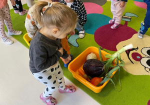 Zdjęcie dziewczynki wskazującej na miskę z jesiennymi warzywami.