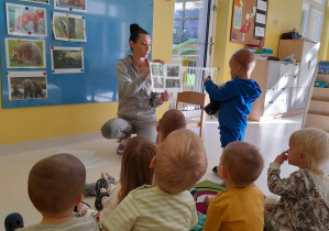 Opiekunka pokazuje maluchowi zdjęcie ze zwierzętami leśnymi.