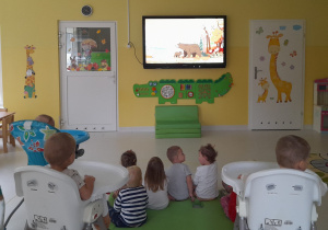 Maluchy oglądające filmik edukacyjny o zwierzętach mieszkających w lesie.