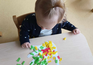 Zdjęcie dziewczynki trzymającej w dłoni kwadracik zielonej bibuły.