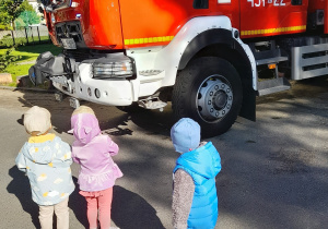 Maluchy przyglądają się wozowi strażackiemu.