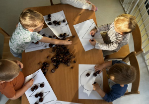 Zdjęcie dzieci podczas pracy plastyczno - sensorycznej przy stoliczku.