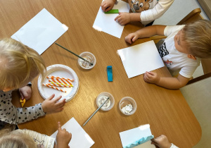 Zdjęcie dzieci podczas zajęć plastycznych przy stoliczku.