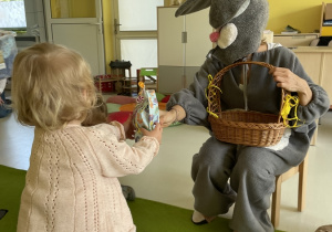 Dziewczynka odbiera prezent od zajączka.