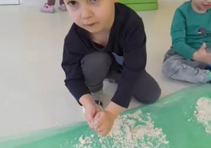 Chłopiec lepi kulki z masy.