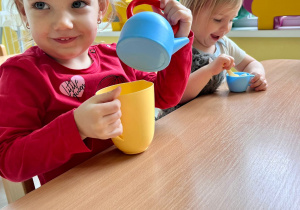 Dziewczynka bawi się plastikowymi naczyniami.